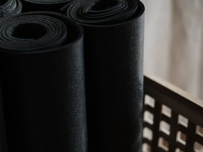 Hands holding a yoga mat in a gym setting.